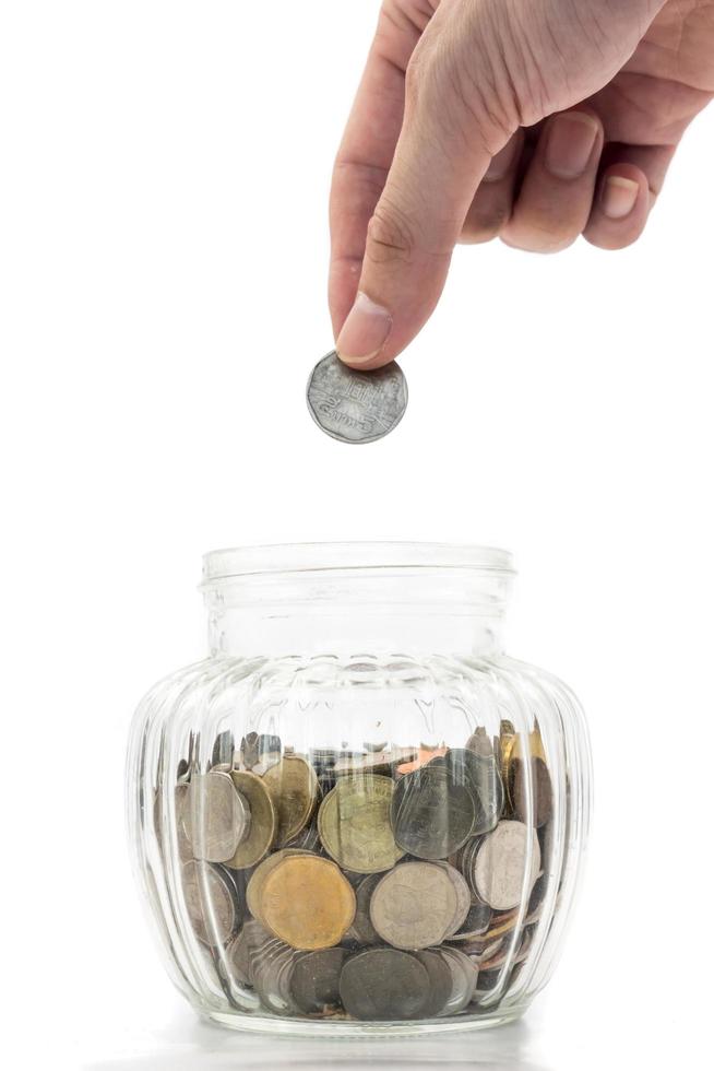 Hand putting a coin into glass bottle on white background, future saving concept photo