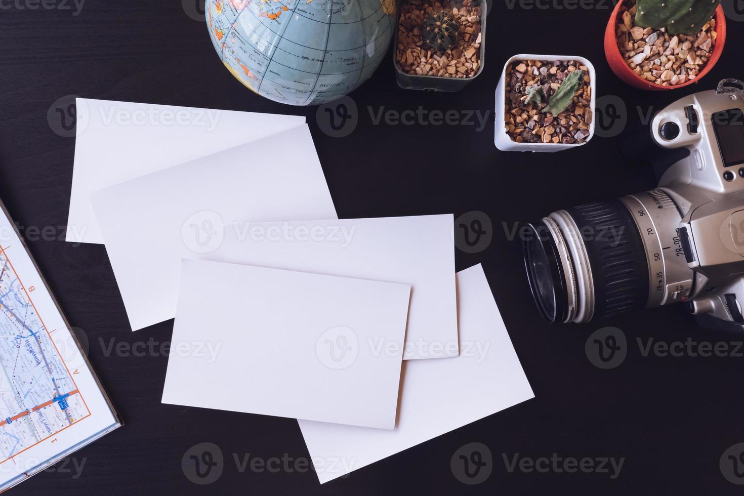 vista superior de tarjetas fotográficas en blanco con cámara, cactus, mapa y globo en el escritorio de la oficina. foto