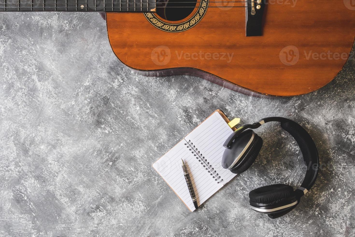 vista superior de la guitarra con auriculares, bolígrafo y cuaderno sobre fondo grunge foto