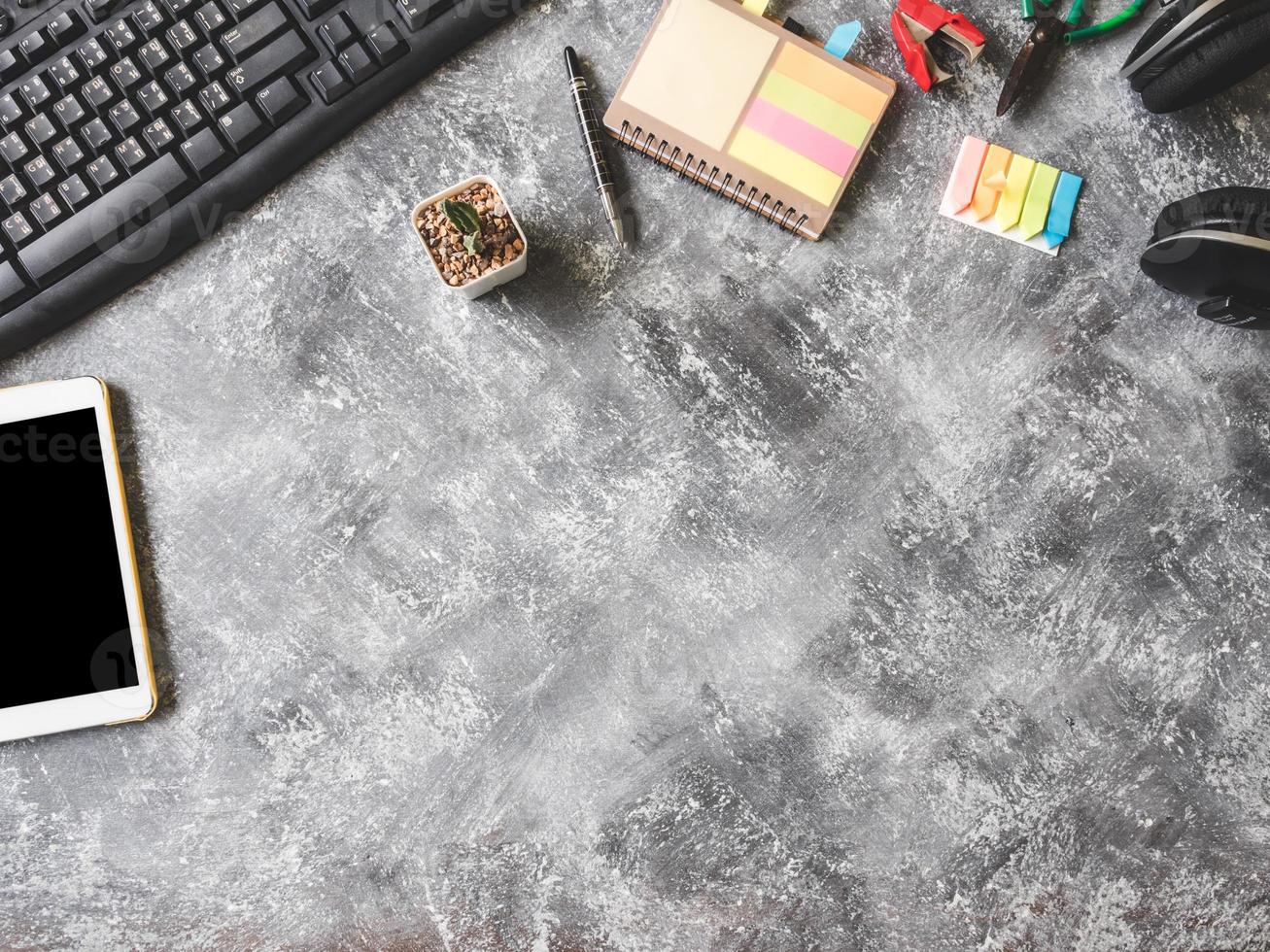 Top view of Keybroad with tablet,headphone,notebook,cactus and Office supplies on Grunge gray background, Free space for text photo