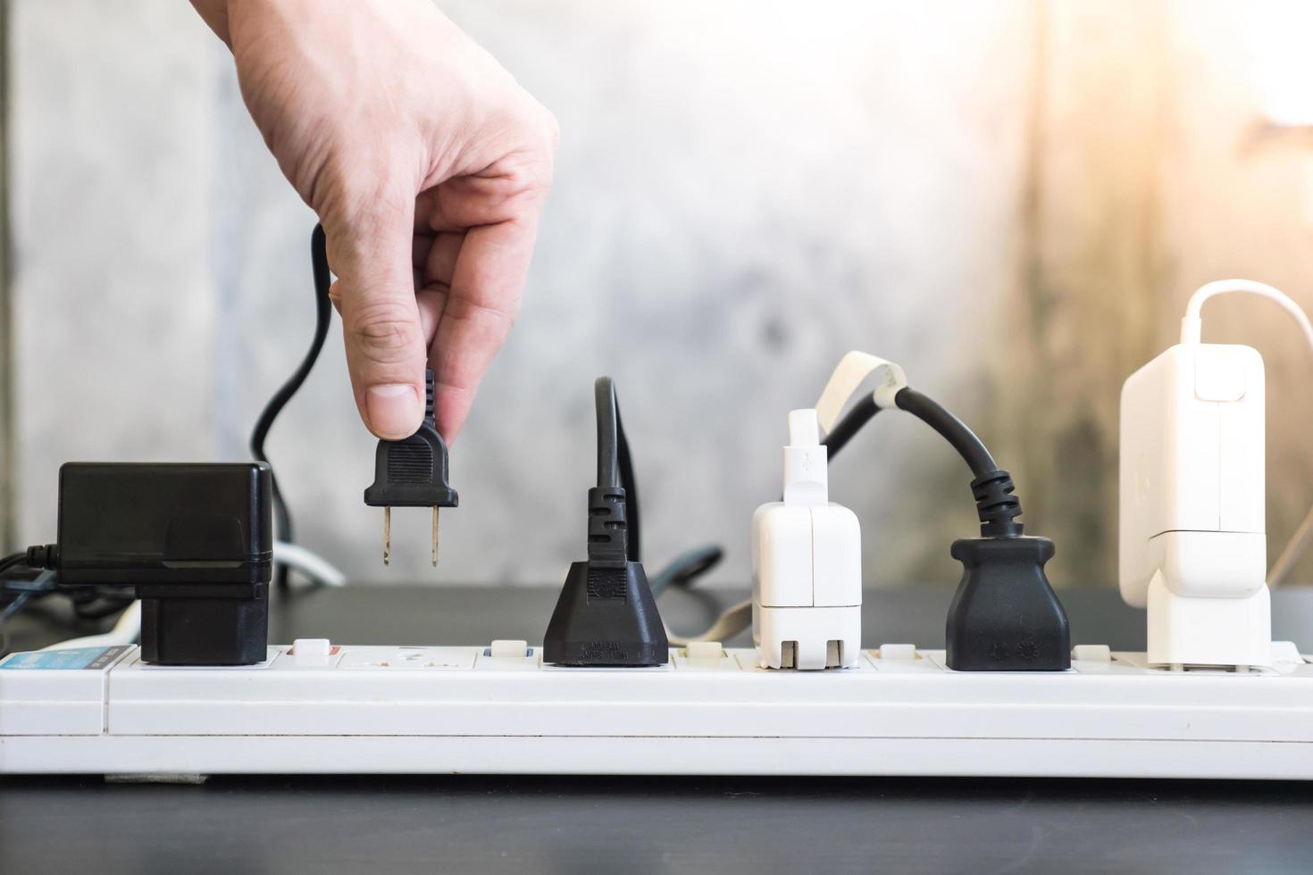 Hand holding electric plug, Multiple socket with connected plugs. photo