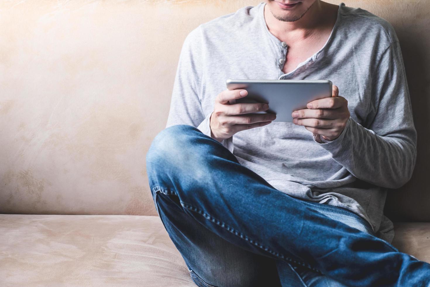 Casual young man using tablet on sofa at home. photo