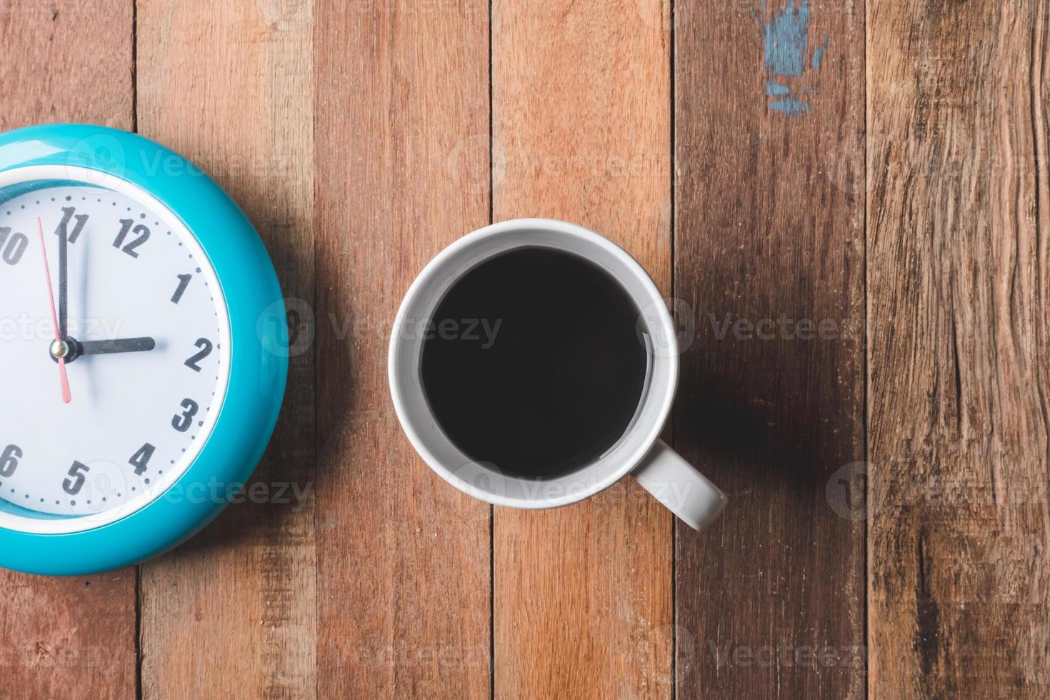 Top view of Coffee cup with clock on wooden table background. photo
