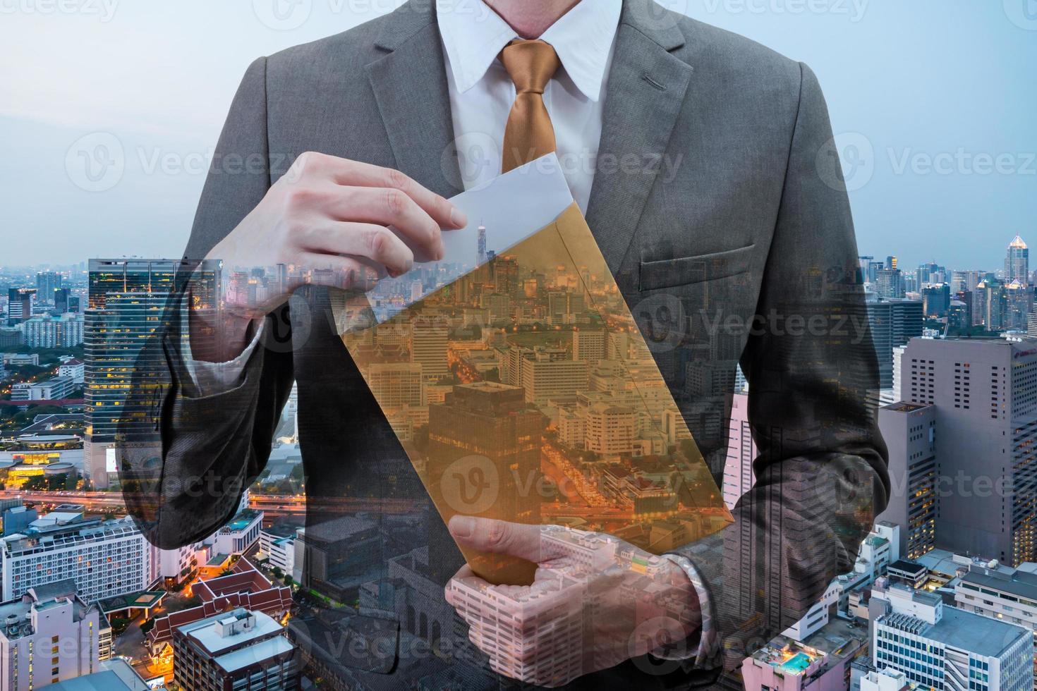 Double exposed of  Businessman holding an envelope with blank sheet with cityscape at night. photo