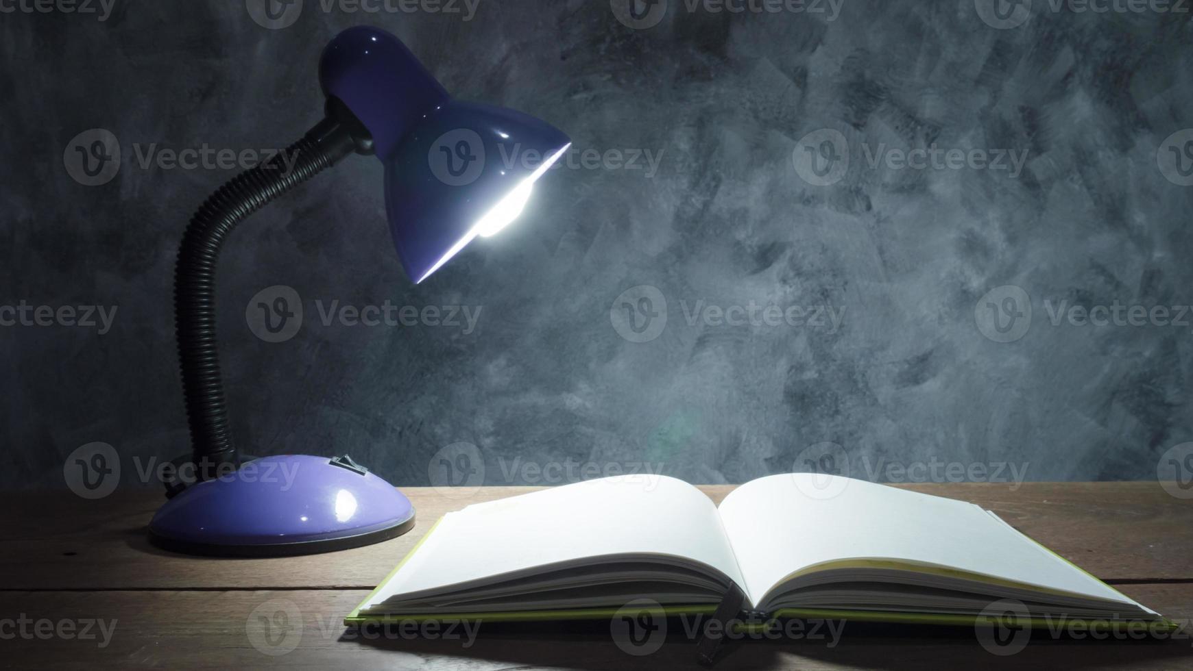 Lamp and notebook on the wooden table with vintage wall background. photo