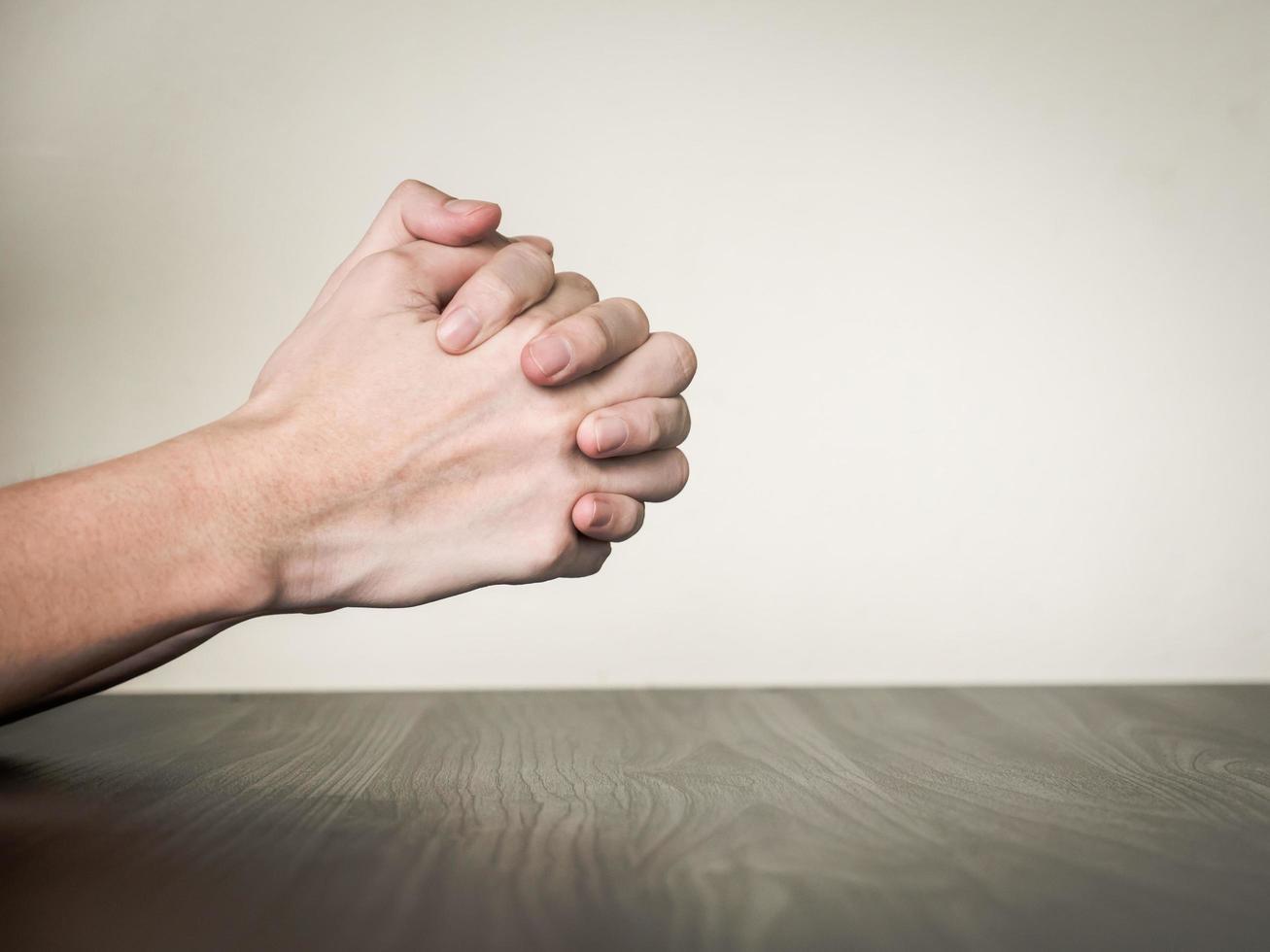 Hands folded together on the table, praying concept photo