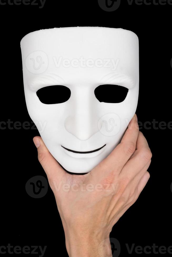 Hand holding white mask on black background. photo