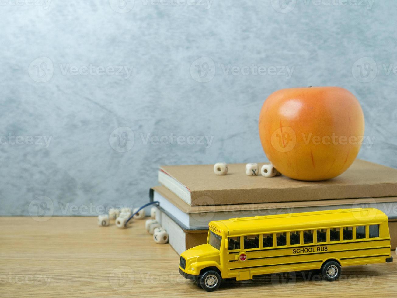 The school bus toy and apple on wood table for back to school or education concept photo