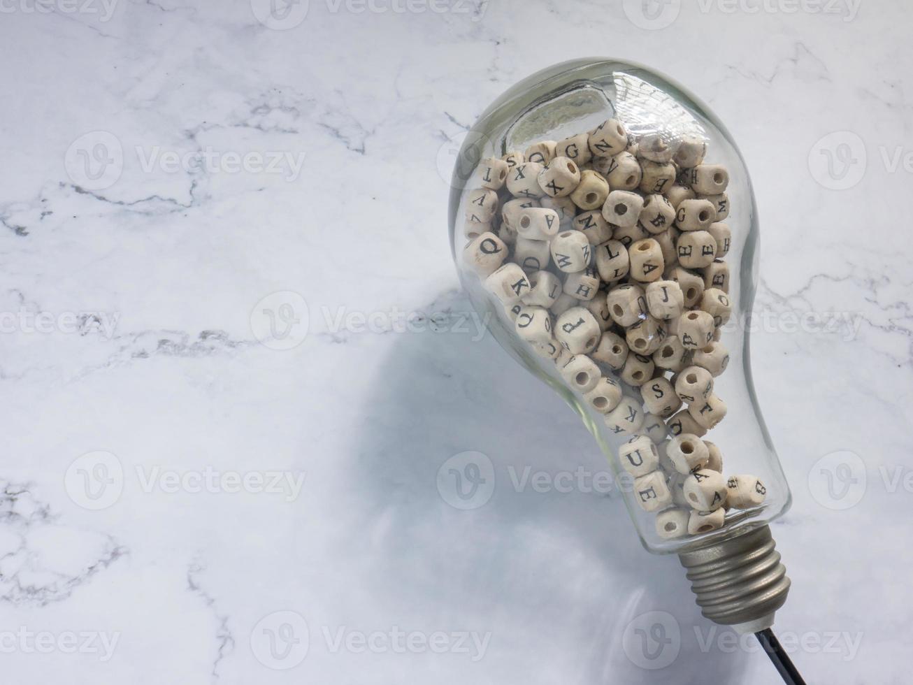 light bulb and alphabet wood cube on white marble for idea or think concept photo