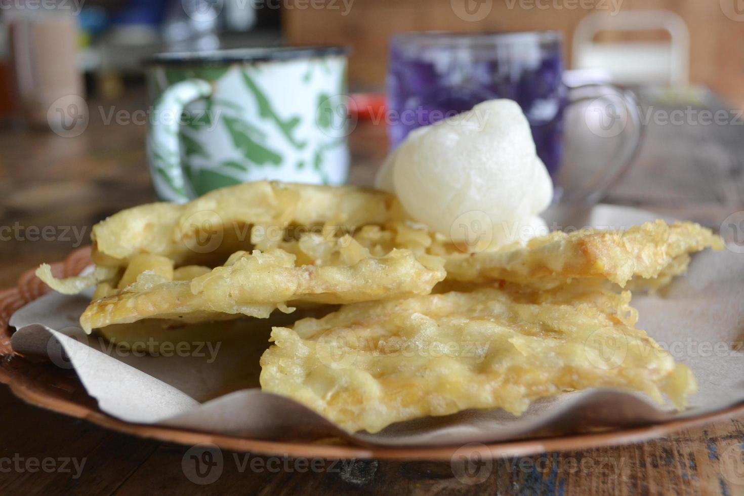Selective Focus Of A Plate Of Fried Tempeh And Geblek With A Background Of A Cup Of Butterfly Pea Tea photo