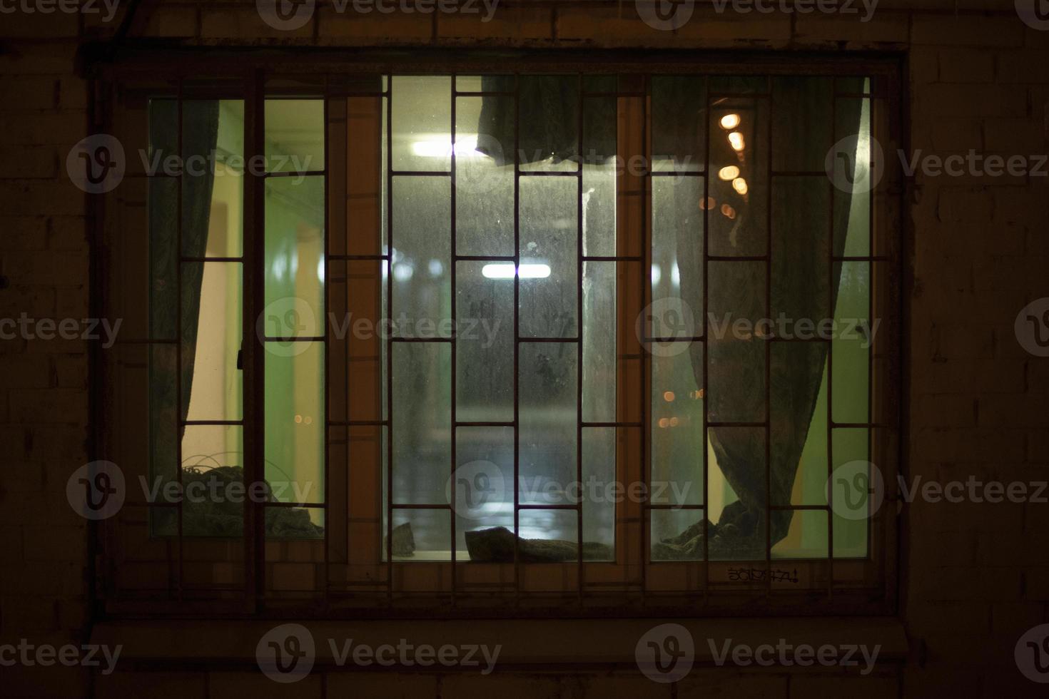 ventana en el edificio por la noche. rejilla en la ventana por la noche. foto