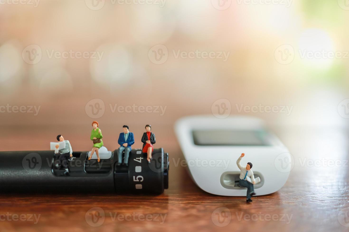 group of businessman and woman miniature figure sitting and talking on lancet and Glucose meter on wooden table with copy space using as Medicine, diabetes, glycemia, health care and people concept. photo