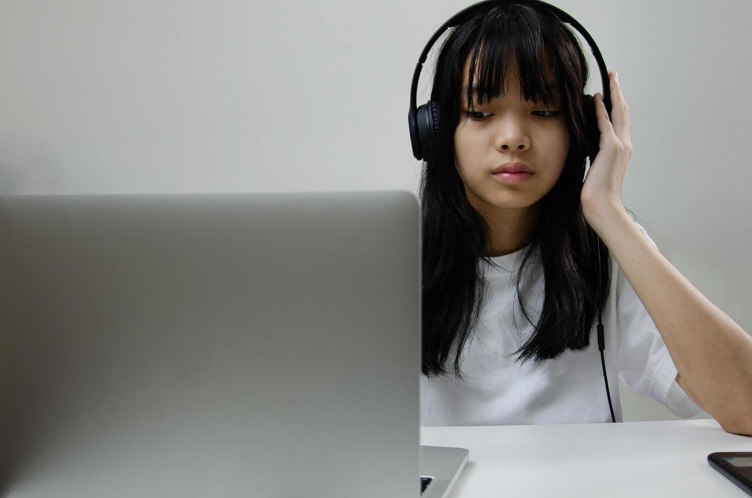 chica con auriculares que estudian en línea con una computadora portátil y escuchan música relajante o juegan en las redes sociales de Internet en casa. foto