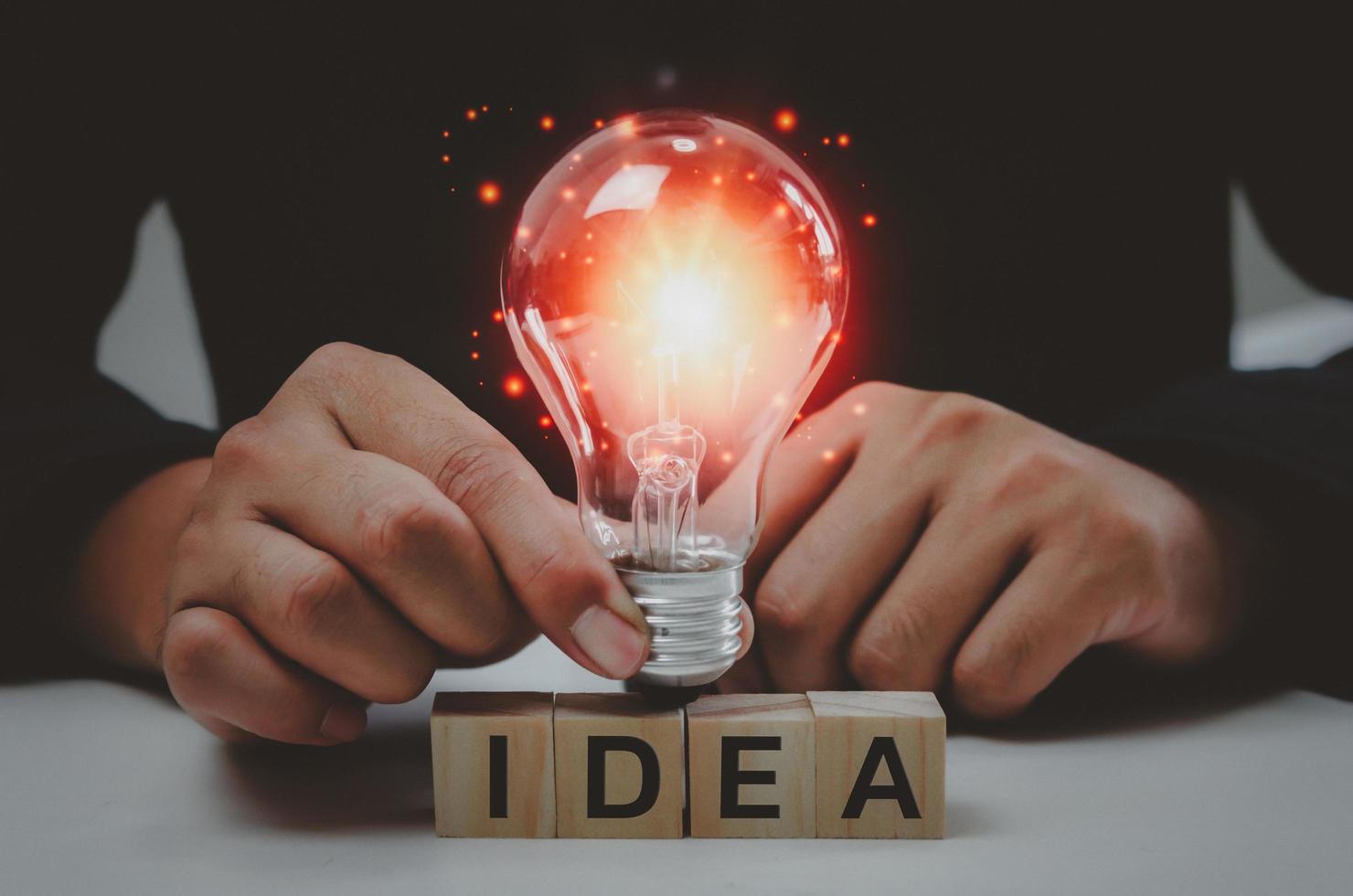 Text idea with a hand holding a light bulb Innovative wood cube block solution photo