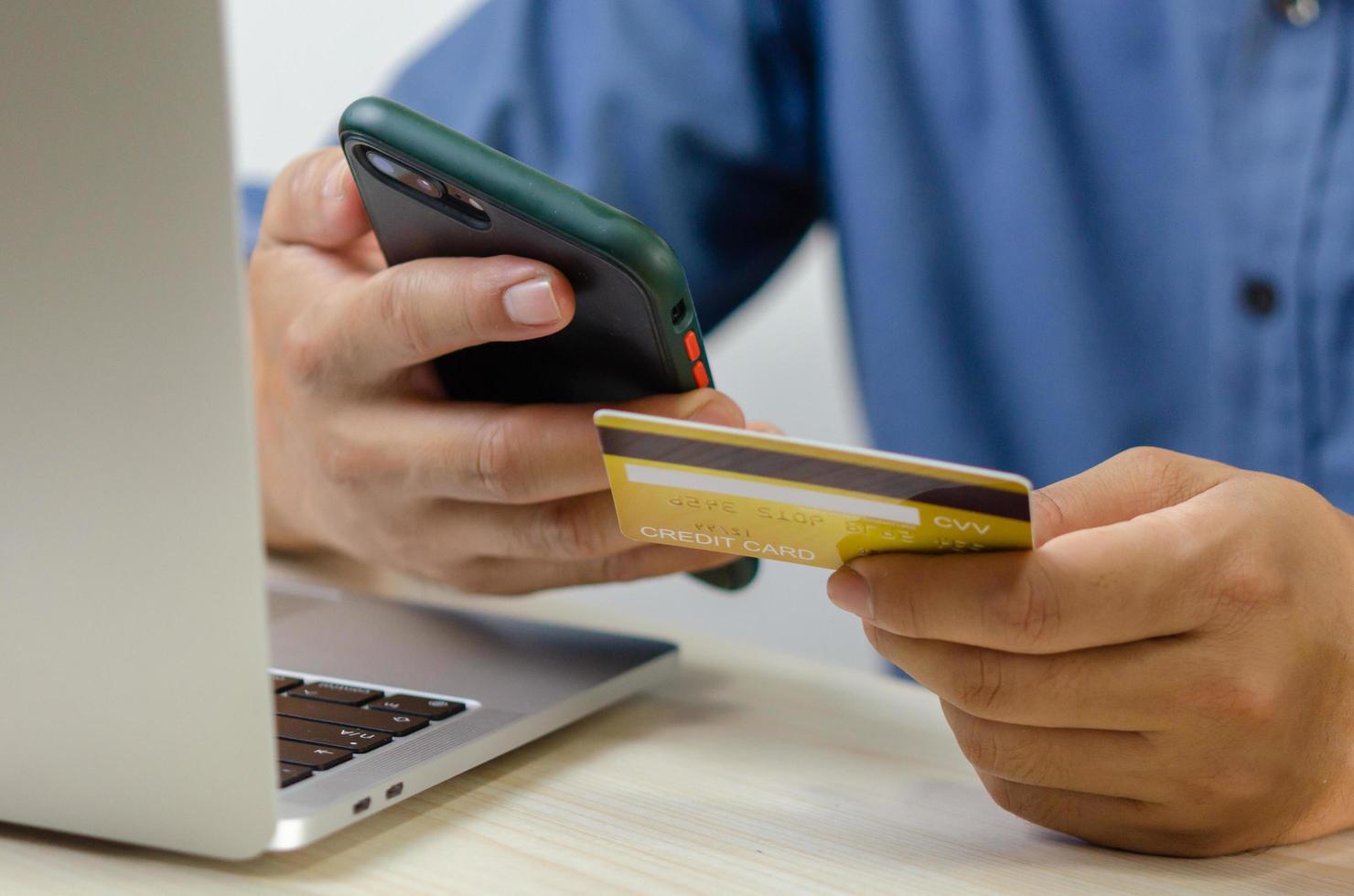 Man hand holding credit card and mobile smart phone with computer laptop.Business finance banking internet and shopping online commerce technology concept. photo