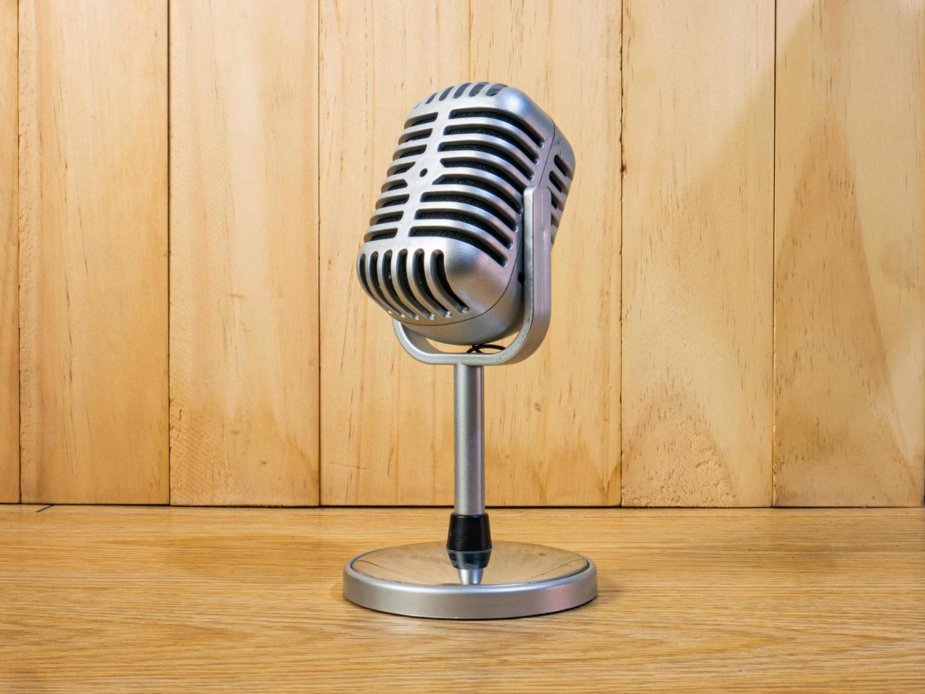 The vintage microphone on wood table for podcast or media concept photo