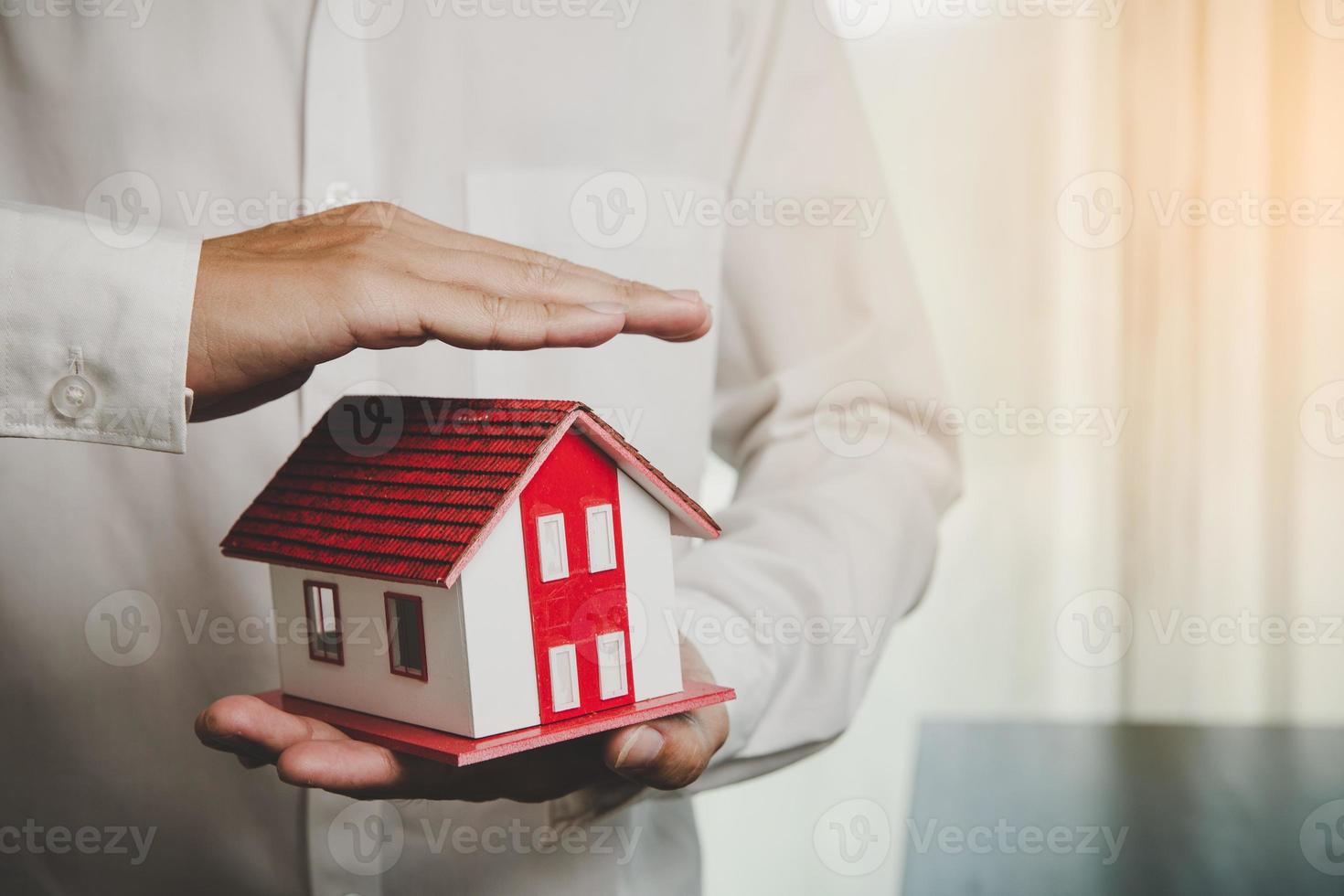 protection or salesman person giving to buyer customer, house in hand, the concept of protecting houses using the gestures and symbols of real estate investors, taking care of credit and contracts. photo