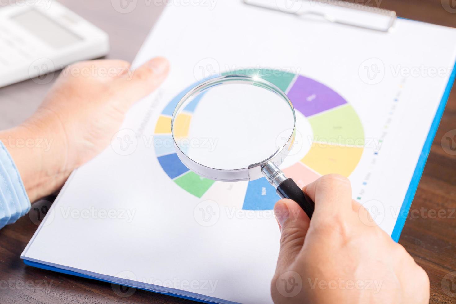 professional business woman hand holding and using magnifying glass search finance document paper on desk in office, businesswoman looking at data with analyzing statistics photo