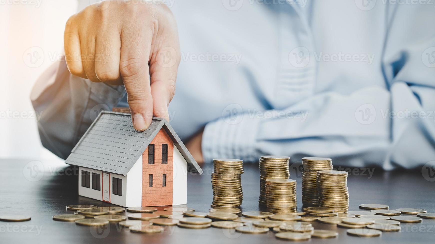 House model with stack coins, business hand is planning savings money of coins for buy home. concept for property ladder, mortgage with real estate investment and saving or investment for a house photo