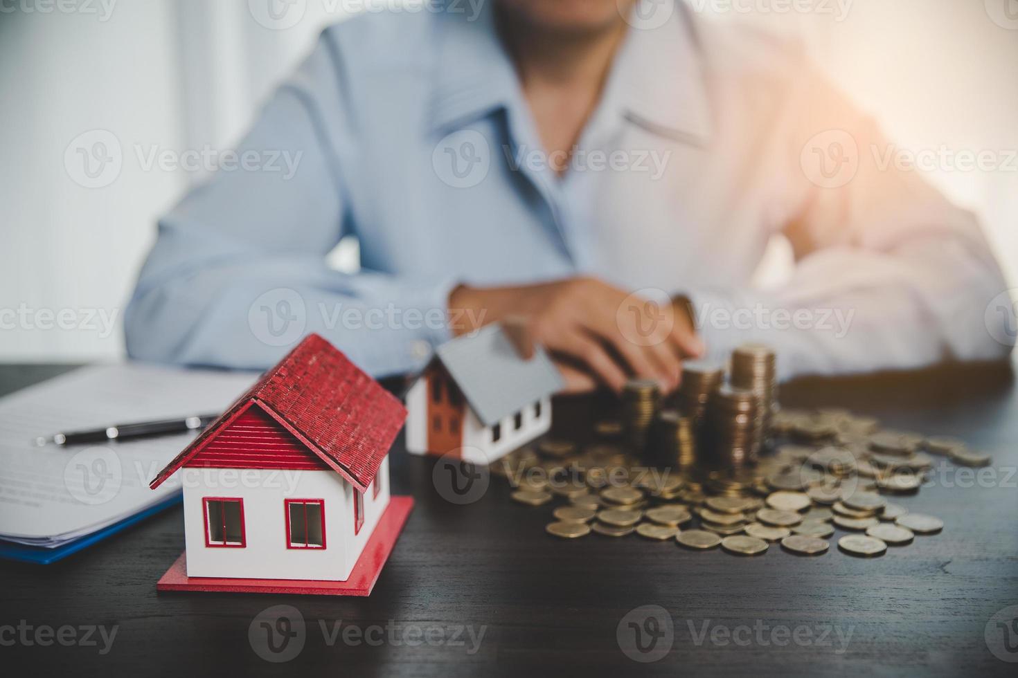 modelo de casa con monedas apiladas, la mano de negocios está planeando ahorrar dinero en monedas para comprar una casa. concepto de escalera de propiedad, hipoteca con inversión inmobiliaria y ahorro o inversión para una casa foto