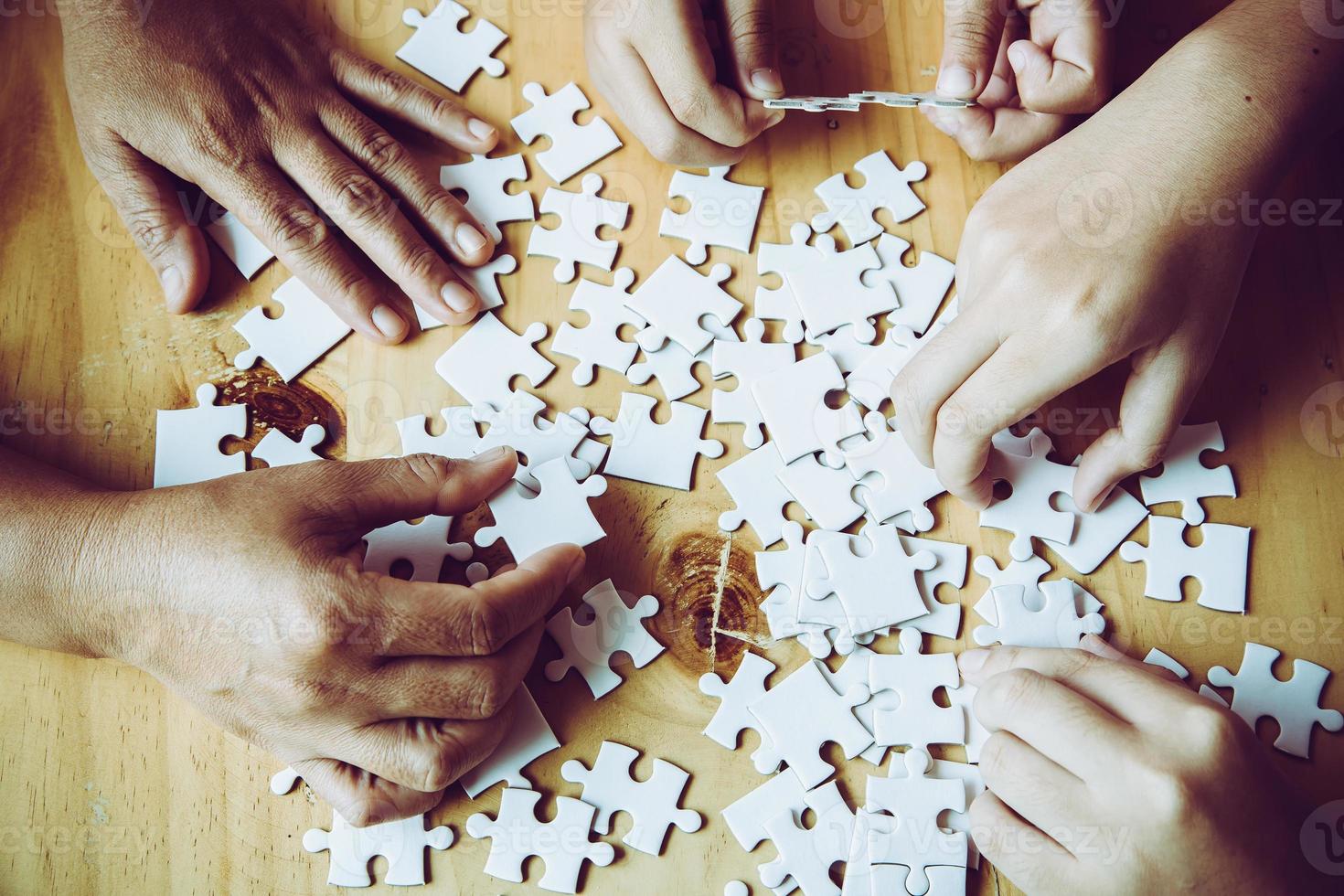 Hands of a person little child and parent playing jigsaw puzzle piece game together on wooden table at home, concept for leisure with family, play with children's development, education and fun. photo