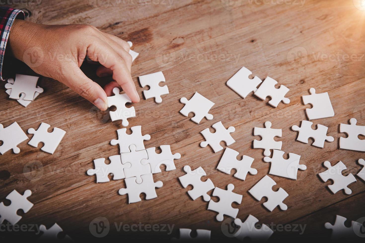 Hands holding jigsaw puzzles piece on wooden table background, success business, solution strategy, teamwork partnership concept photo