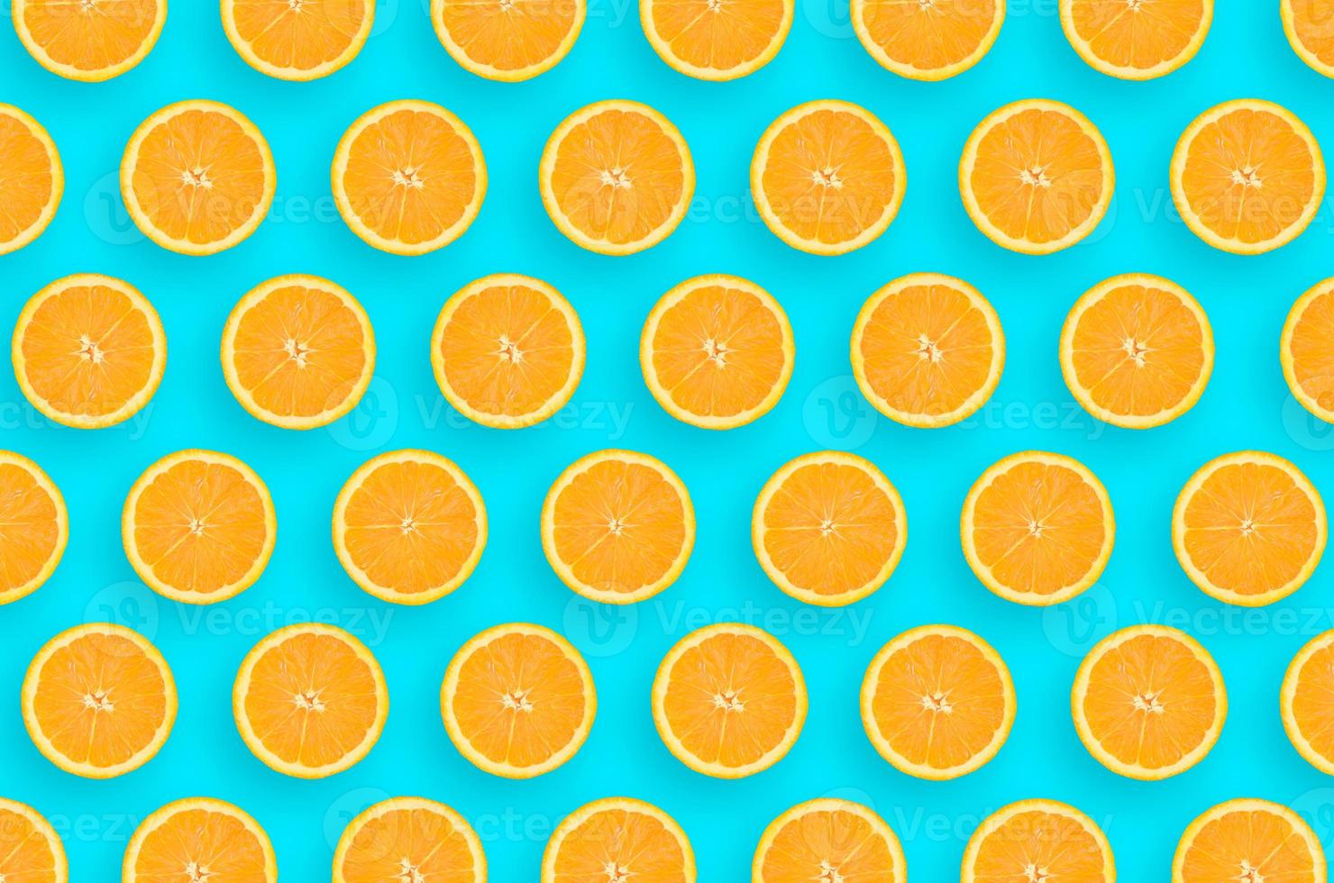 Pattern of an orange citrus slices on bright blue background photo