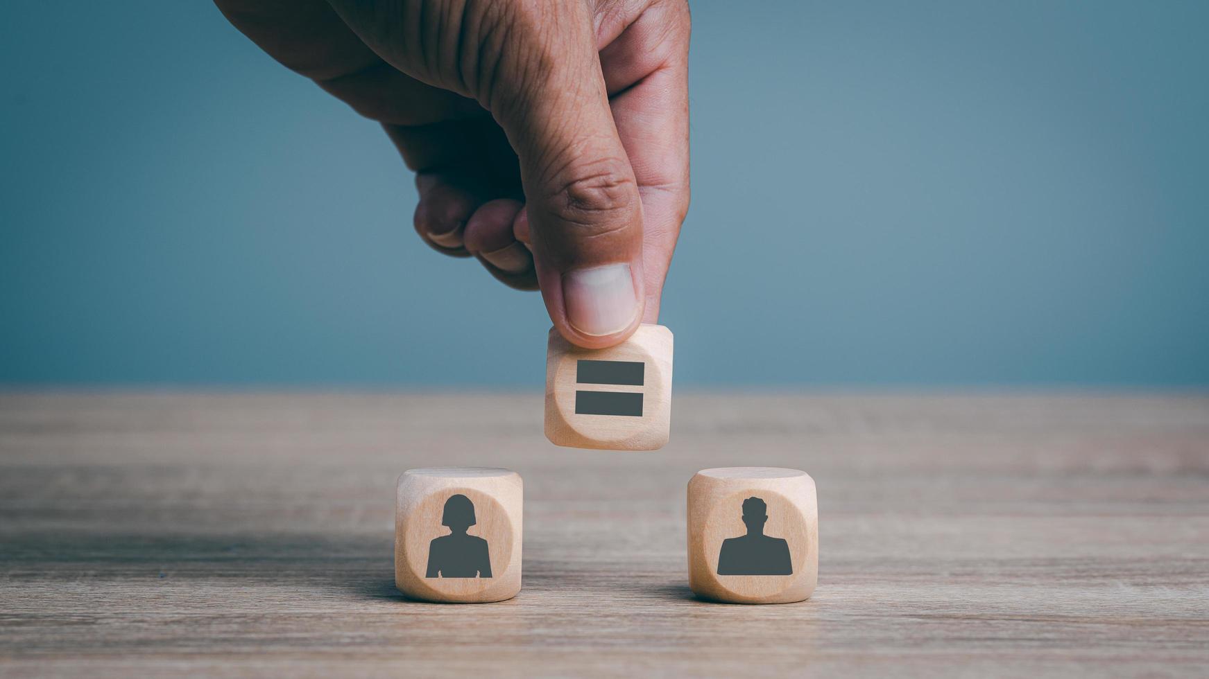 la mano del hombre está colocando bloques de madera sobre la mesa, conceptos de igualdad de género, discriminación humana, libertades y cuestiones de género, reduciendo la desigualdad social. foto