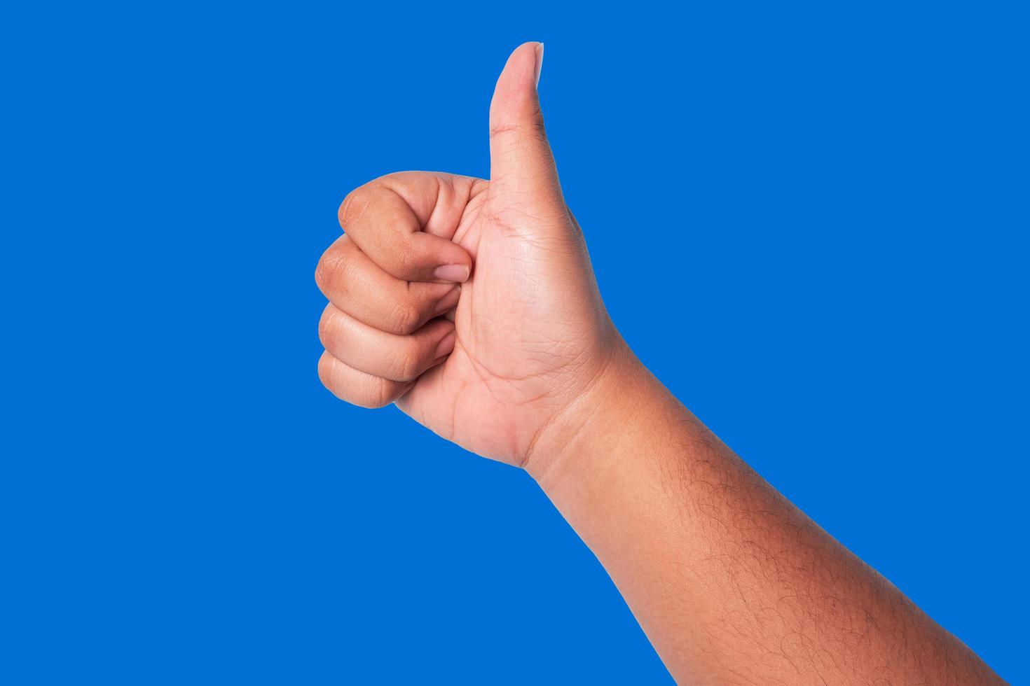 person's hand showing thumbs up, concept showing good appreciation, and okay or agree, isolated on blue background photo