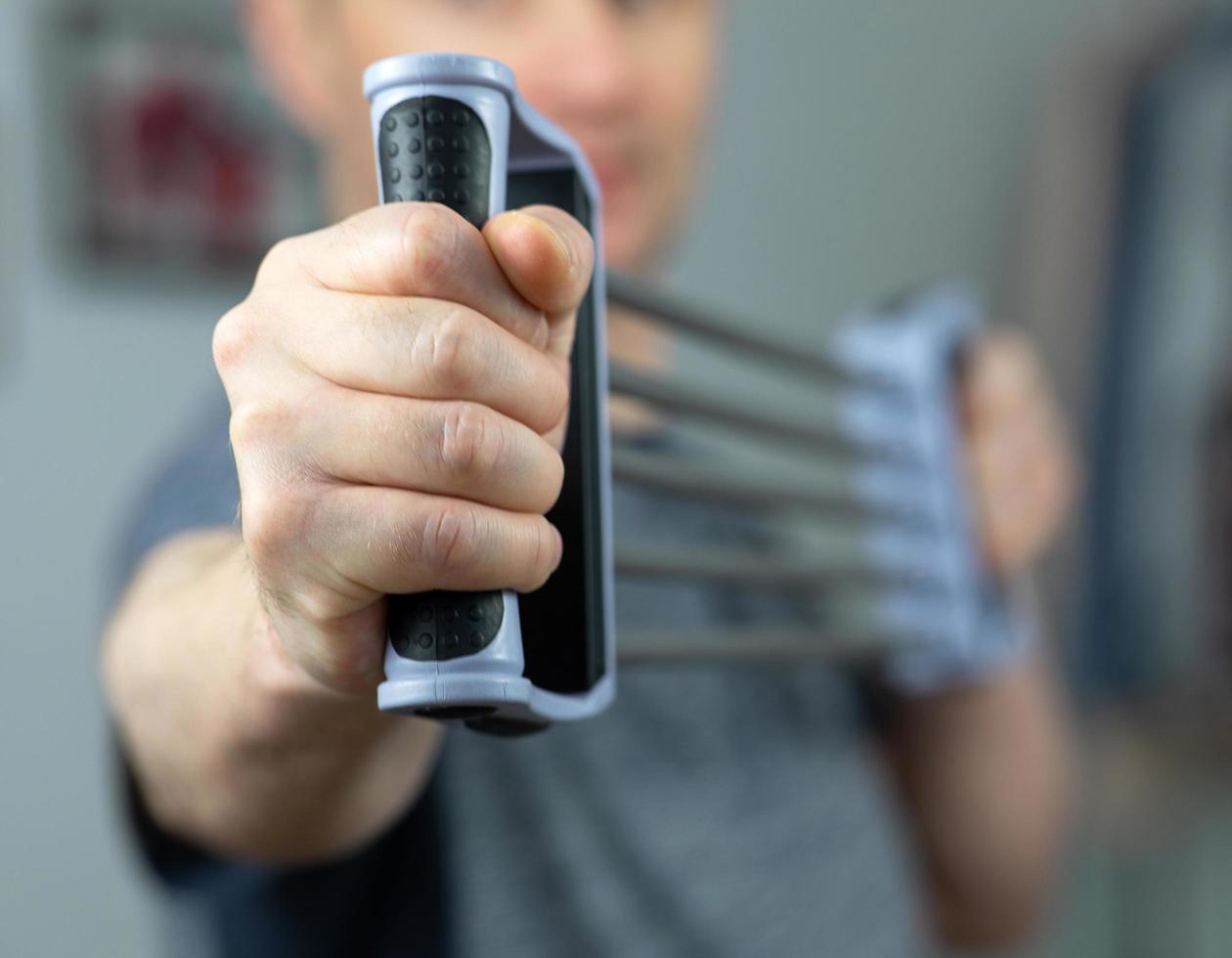 Man doing fitness exercises with expander at home photo