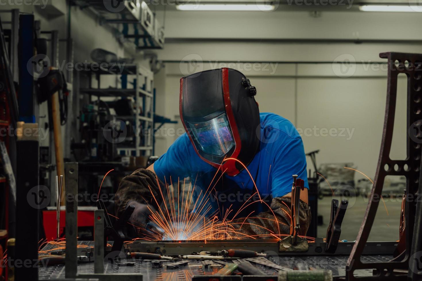 Professional Heavy Industry Welder Working Inside factory, Wears Helmet and Starts Welding. Selective Focus photo