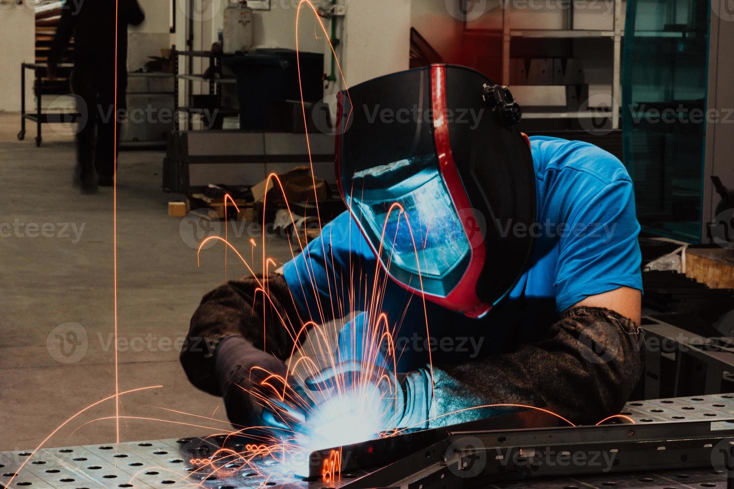 Professional Heavy Industry Welder Working Inside factory, Wears Helmet and Starts Welding. Selective Focus photo