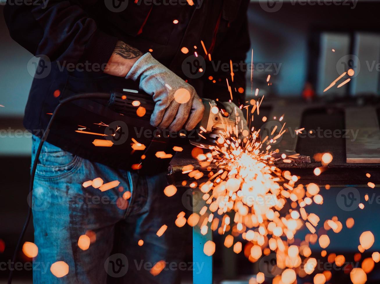 interior de fábrica de ingeniería de industria pesada con trabajador industrial usando amoladora angular y cortando un tubo de metal. contratista en estructuras metálicas de fabricación de cascos y uniformes de seguridad. foto