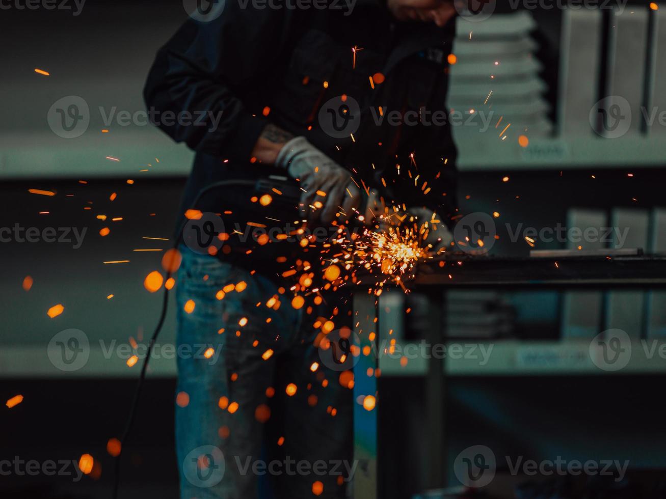 interior de fábrica de ingeniería de industria pesada con trabajador industrial usando amoladora angular y cortando un tubo de metal. contratista en estructuras metálicas de fabricación de cascos y uniformes de seguridad. foto