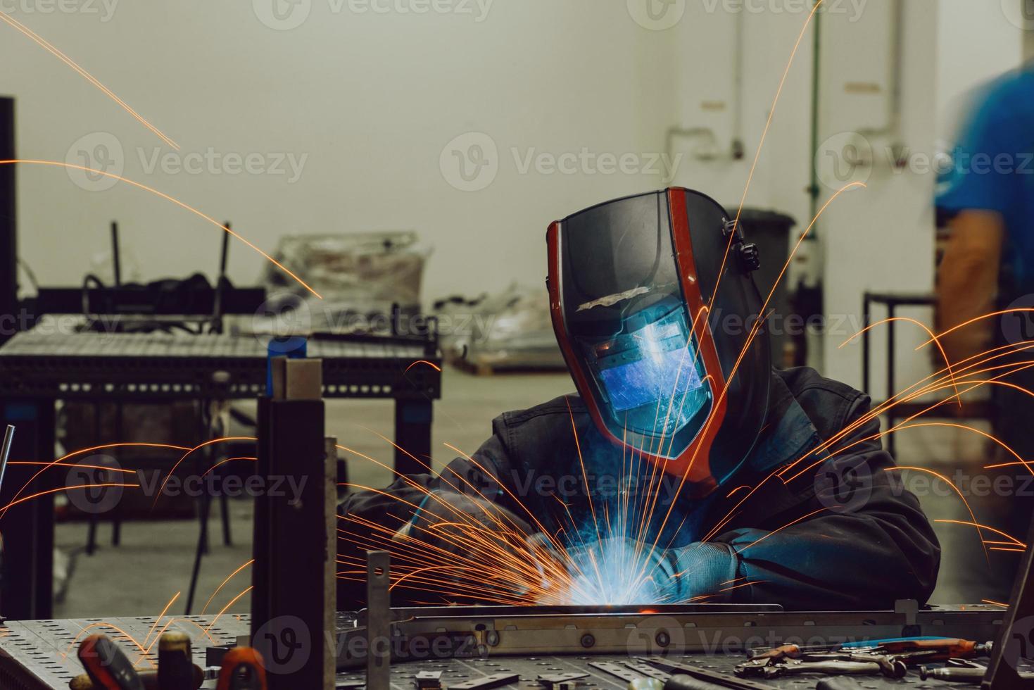 Professional Heavy Industry Welder Working Inside factory, Wears Helmet and Starts Welding. Selective Focus photo