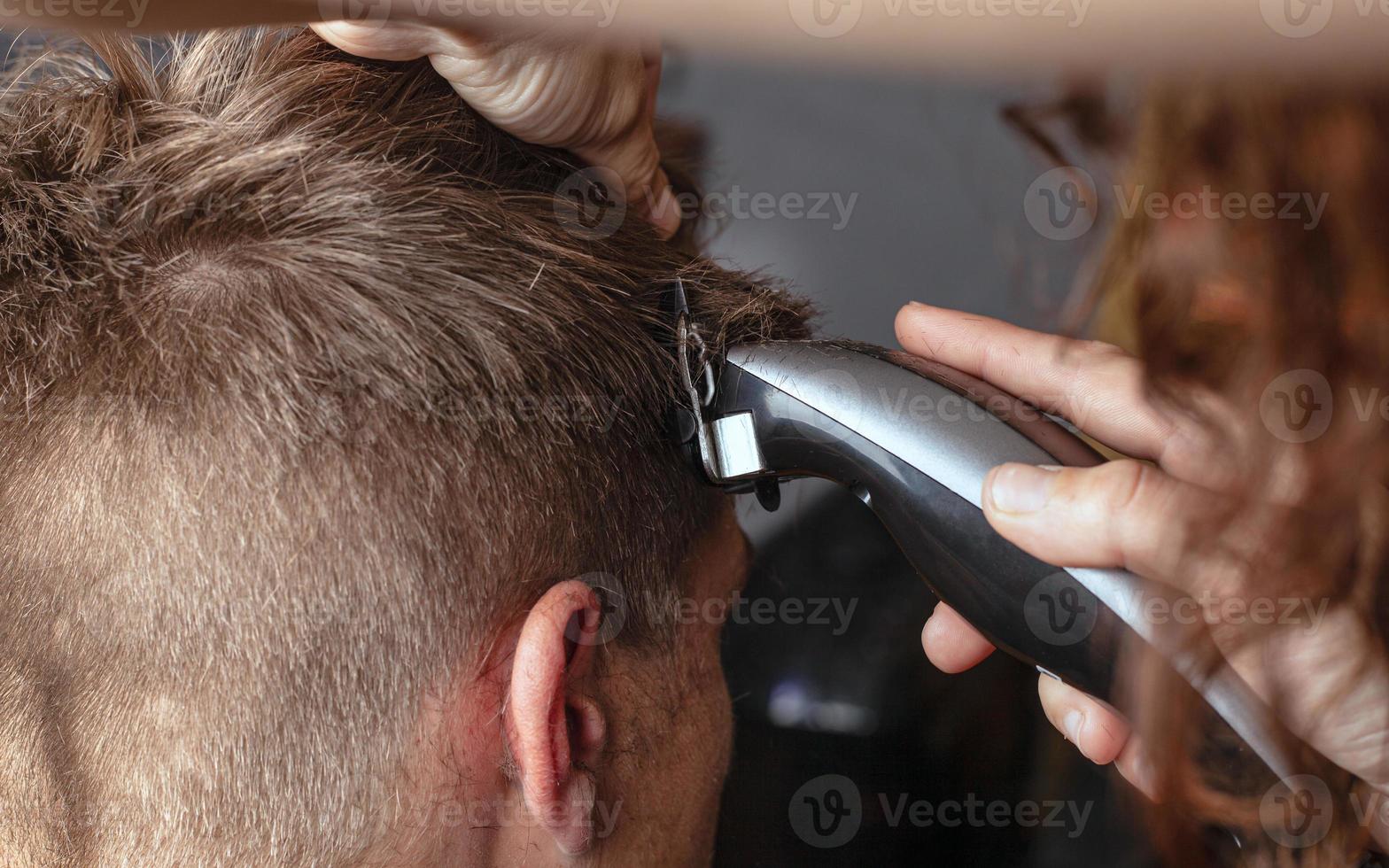 cutting hair with a trimmer, hairdresser shaves hair photo