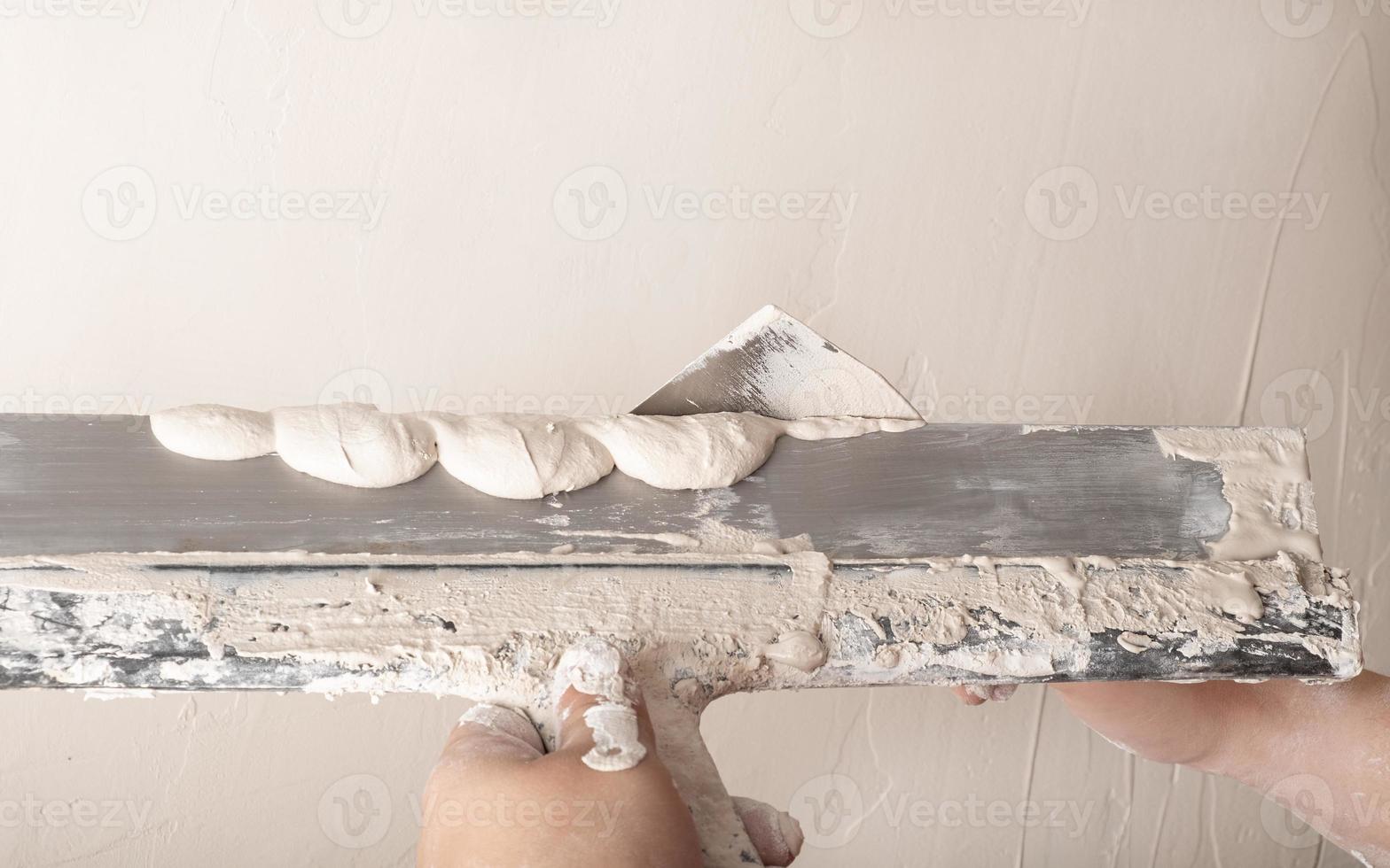 Builder plastering with a spatula and smoothing the wall with plaster photo