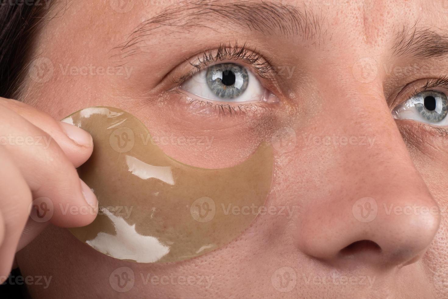 applying patches to tired eyes female face close-up photo