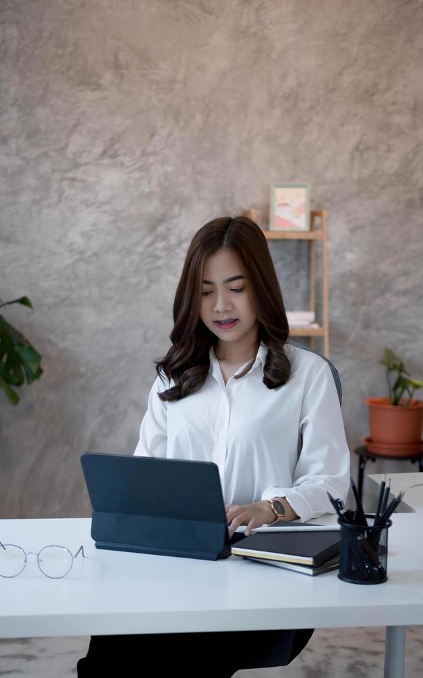Charming asian businesswoman sitting working on laptop in office. photo