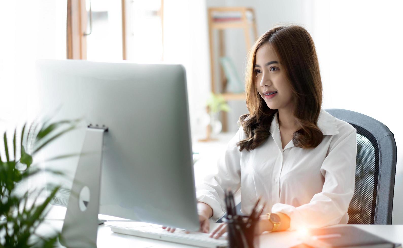 Beautiful young asian woman sitting at coffee shop using laptop. Happy young businesswoman sitting at table in cafe with tab top computer. photo