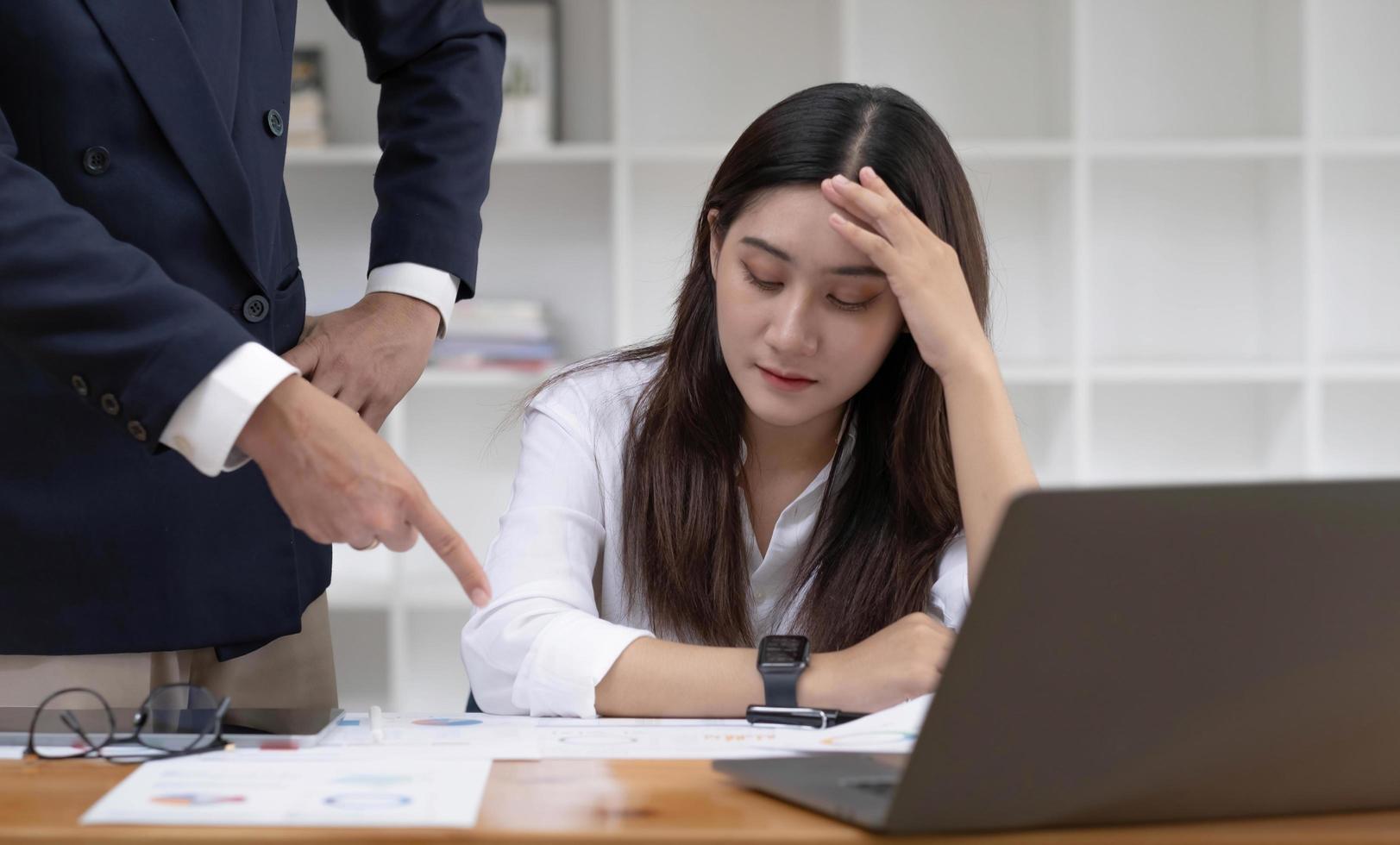 joven empresaria asiática cansada y aburrida o trabajadora de oficina recibiendo una queja de su jefe masculino en la oficina sobre su desempeño laboral. foto