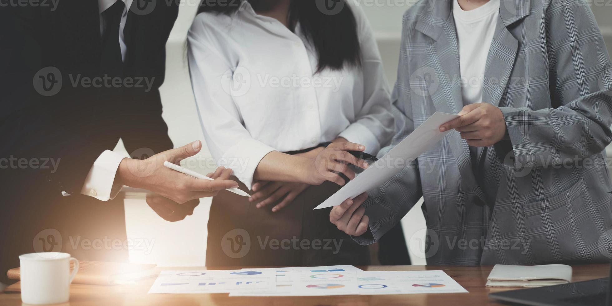 Close up of diverse businesspeople cooperate work together discussing company financial statistics, multiracial colleagues employees collaborate brainstorm with finance document at meeting photo