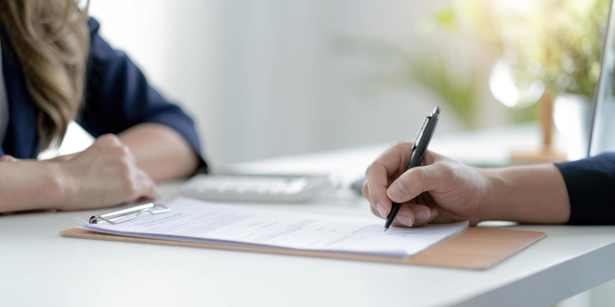 Close up of young woman job applicant being hired on vacant place signing employment contract in presence of recruiter, female bank client putting signature under financial document photo