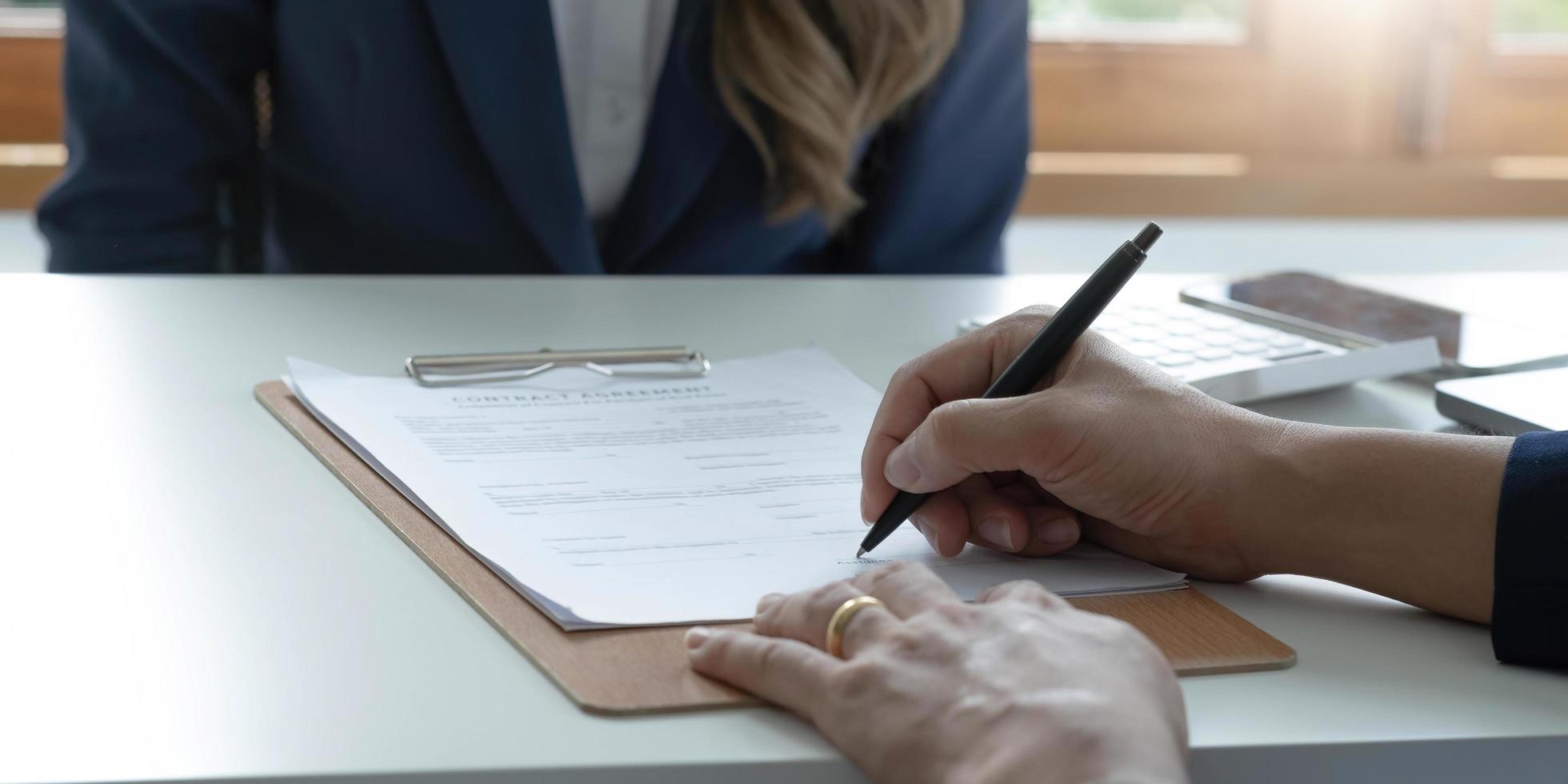 Close up of male hand putting signature, running own small business, have a contract in place to protect it, basics of writing contract, one sentence in a contract can cost a business. photo