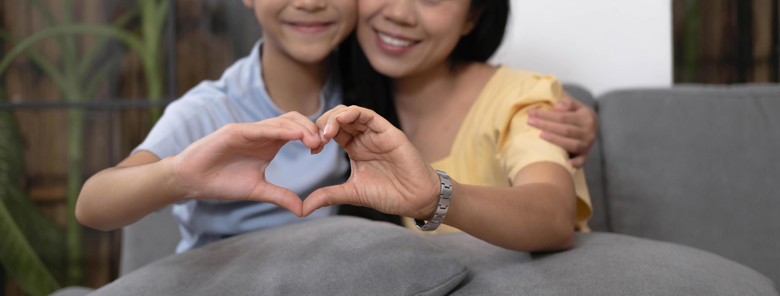 Asian mother and daughter making heart with their hands and smiling to camera. Life insurance, love and support in family relationships concept photo