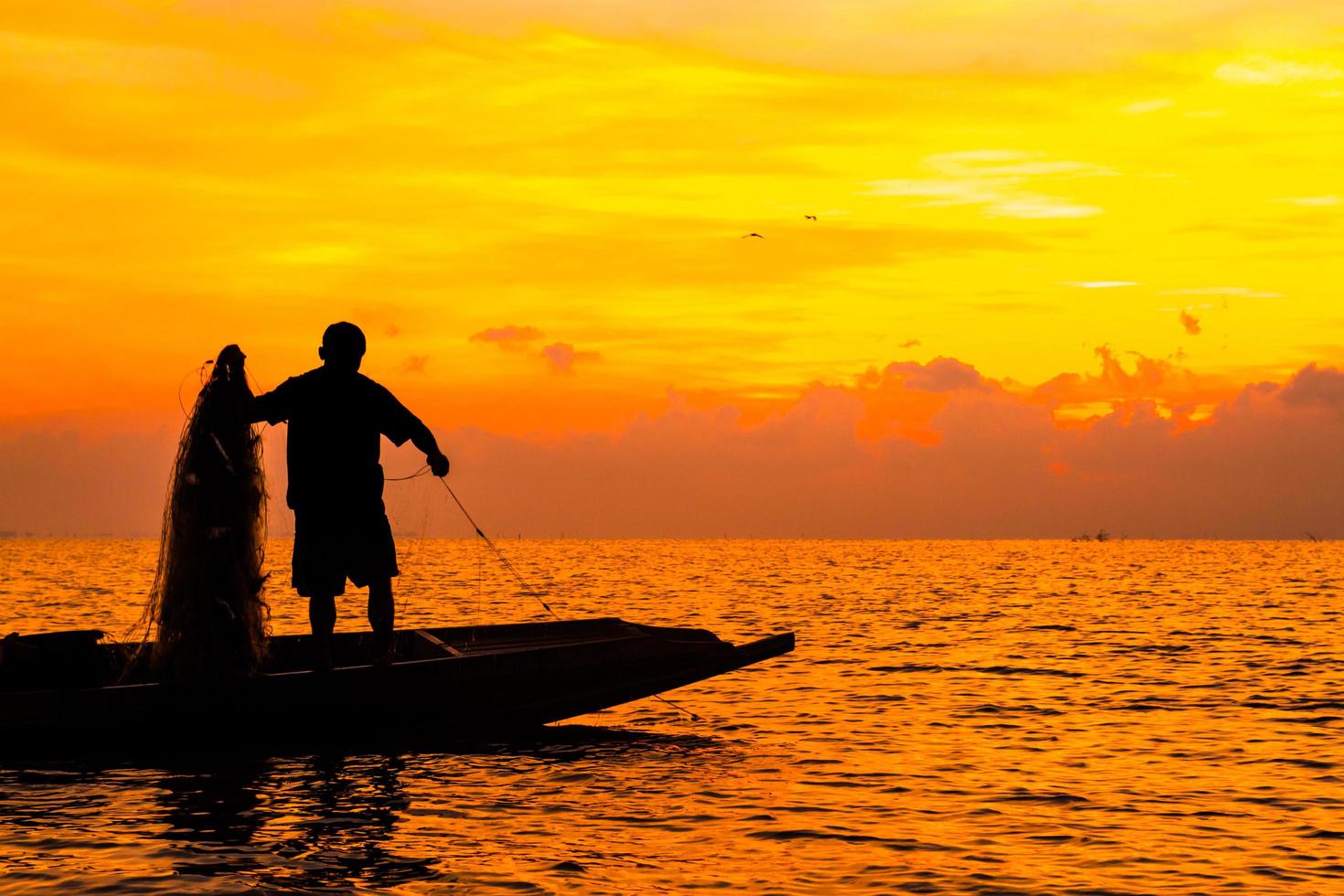 silueta de pescadores pescando en el lago a la hora del amanecer. foto