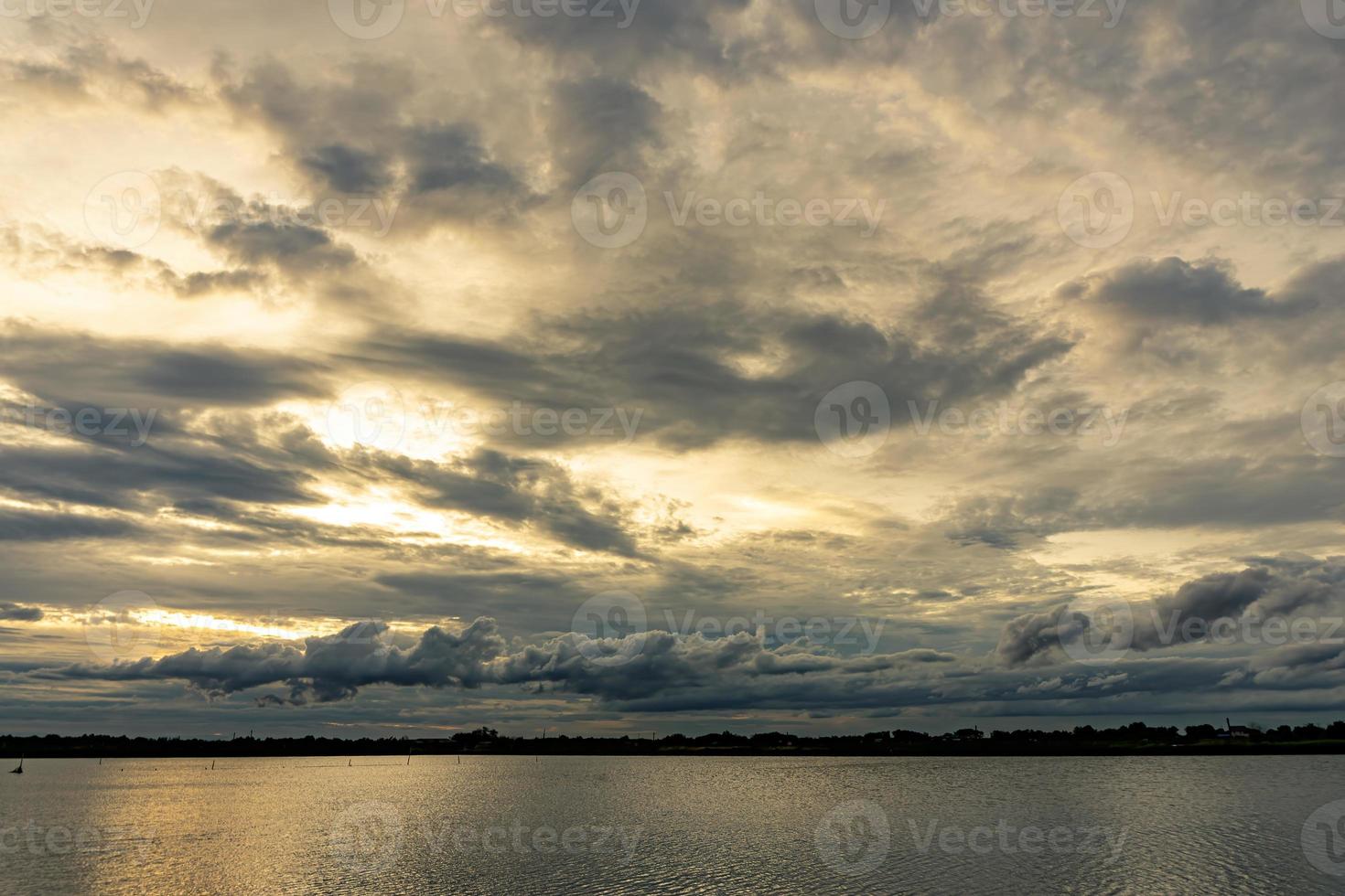 las nubes llenaron el cielo, oscureciendo la luz del sol durante la puesta del sol. el cielo en la parte superior está coloreado de naranja por el sol. el cielo inferior es negro y gris por las nubes de lluvia. foto