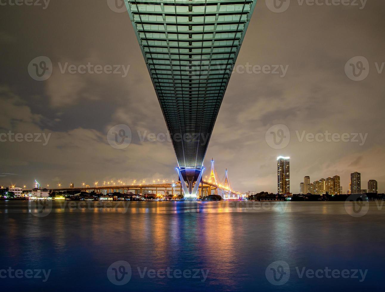 Green led light under the bridge over the river On a cloudy day in the sky. Bhumibol Bridge, Samut Prakan, Thailand photo