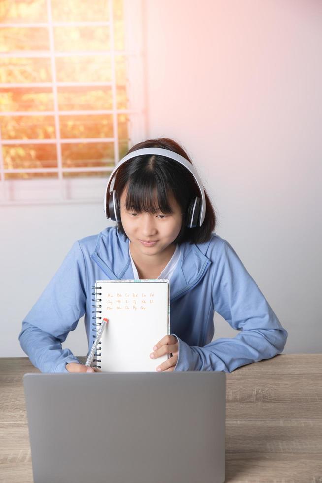 una joven asiática está sentada en casa estudiando. foto