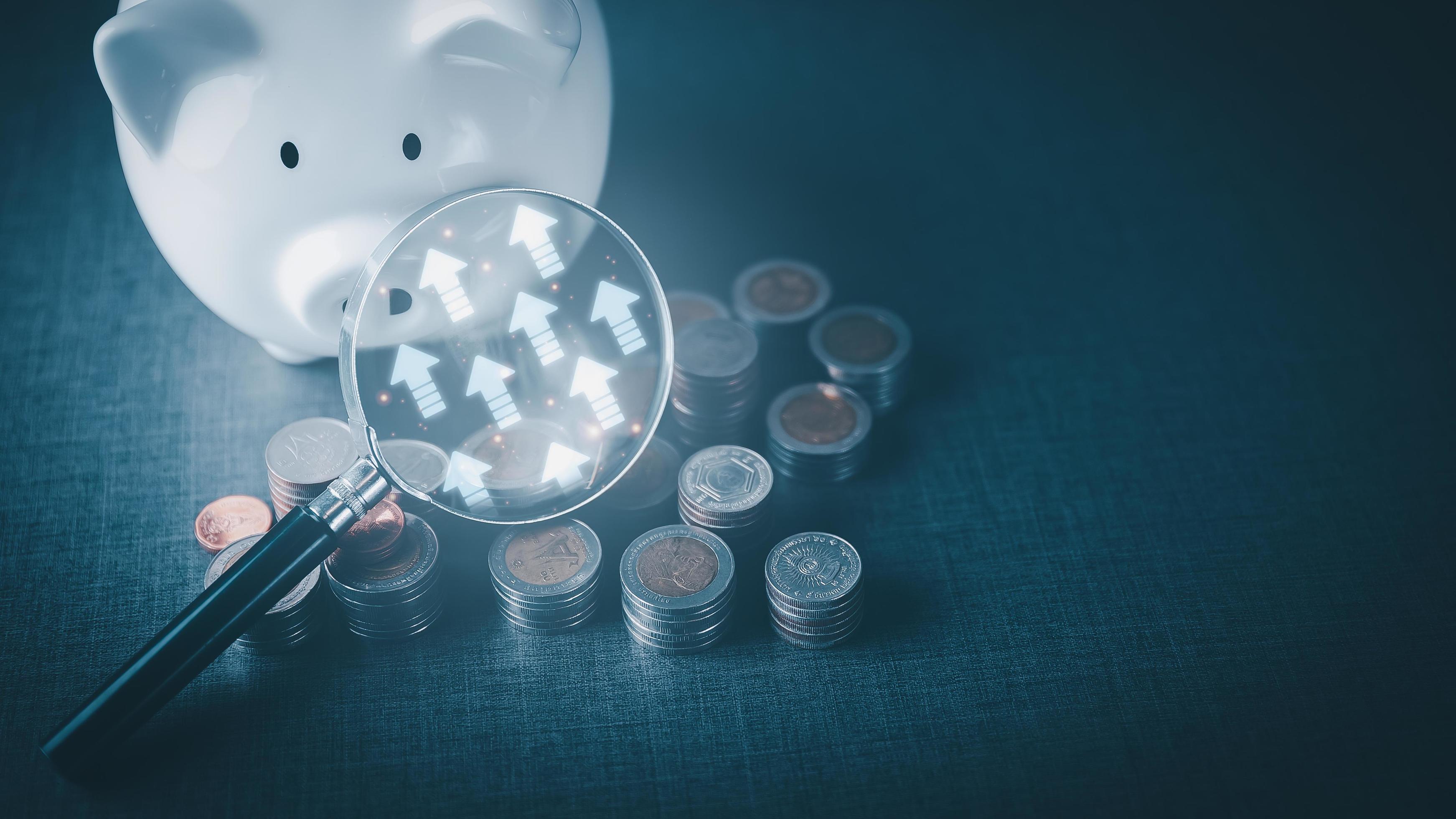 Magnifying glass on a pile of money coins. Stock Photo